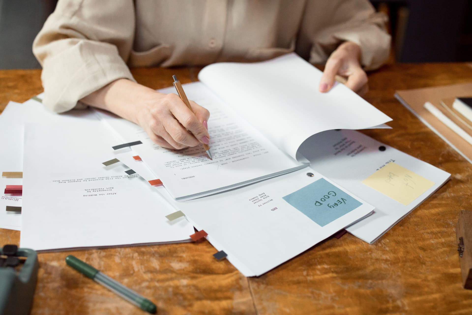 An editor marking up printed manuscript pages with a pencil at a desk